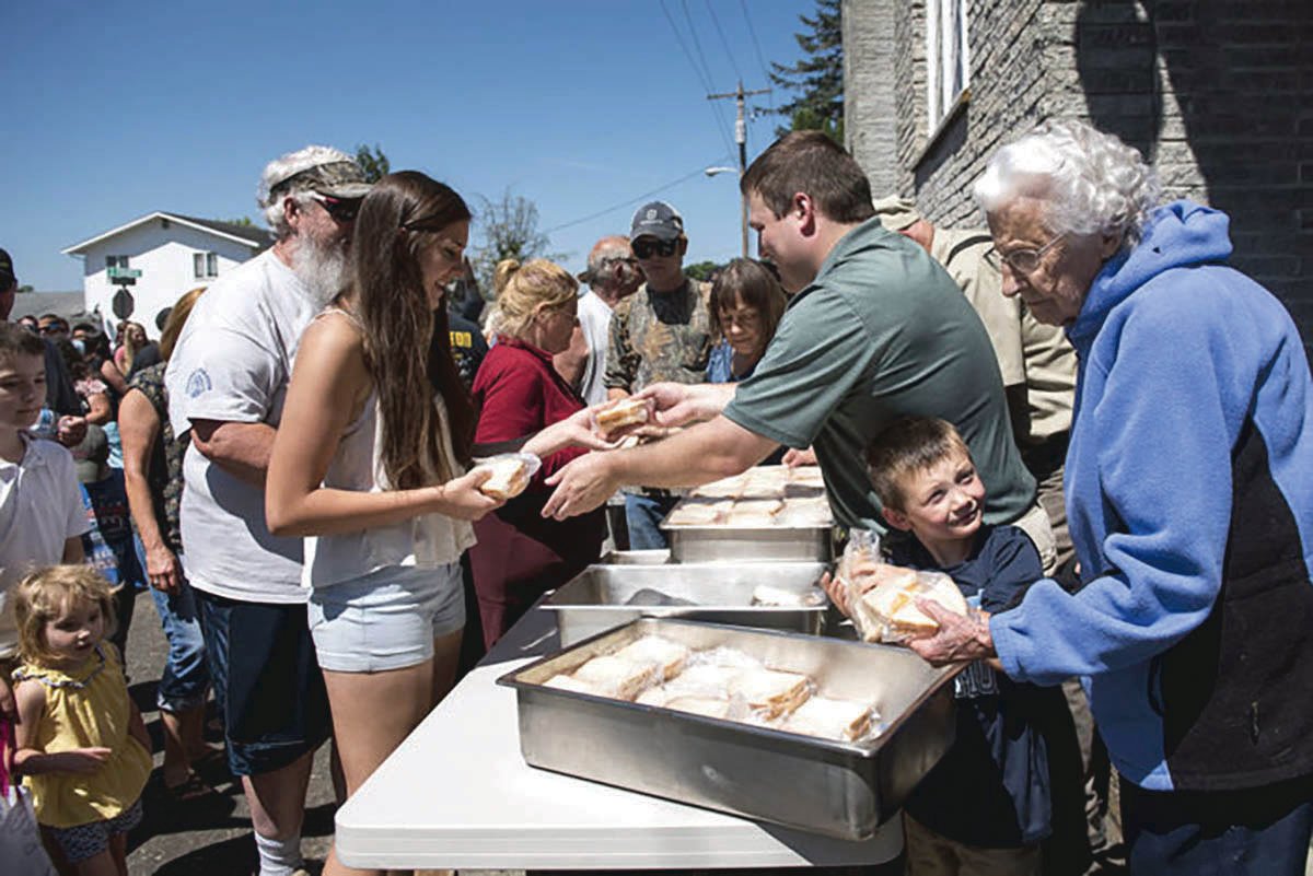 Volunteers hand out free cheese sandwiches Saturday after the 2018 Toledo Cheese Days parade.